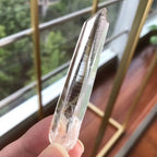 Lemurian clear quartz crystal point with natural horizontal striations and exceptional clarity, ideal for crystal collectors and display.