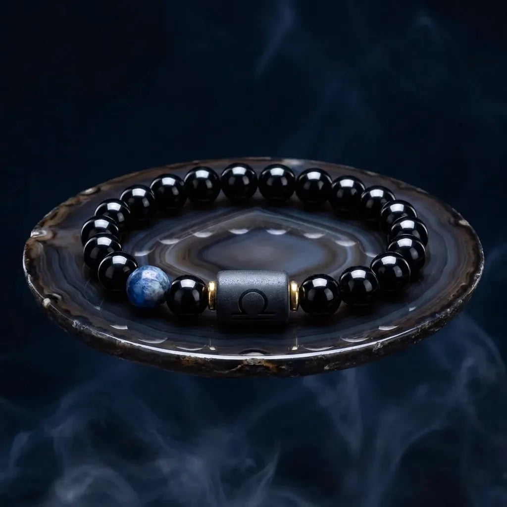 Black beaded bracelet with a blue stone on an agate stone against a dark background