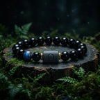 Libra zodiac bracelet with glossy black beads, blue accent stone, and engraved center bead on a forest stump.