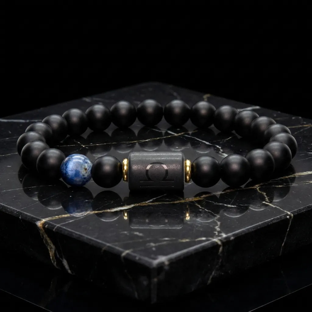 Libra zodiac bracelet with matte black beads, blue accent stone, and engraved center bead on engraved stone surface.