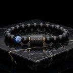 Libra zodiac bracelet with matte black beads, blue accent stone, and engraved center bead on engraved stone surface.