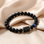 Libra zodiac bracelet with matte black beads, blue accent stone, and engraved center bead on beige satin.