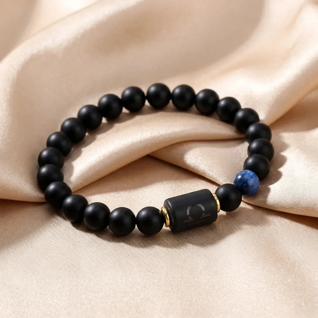 Libra zodiac bracelet with matte black beads, blue accent stone, and engraved center bead on beige satin.
