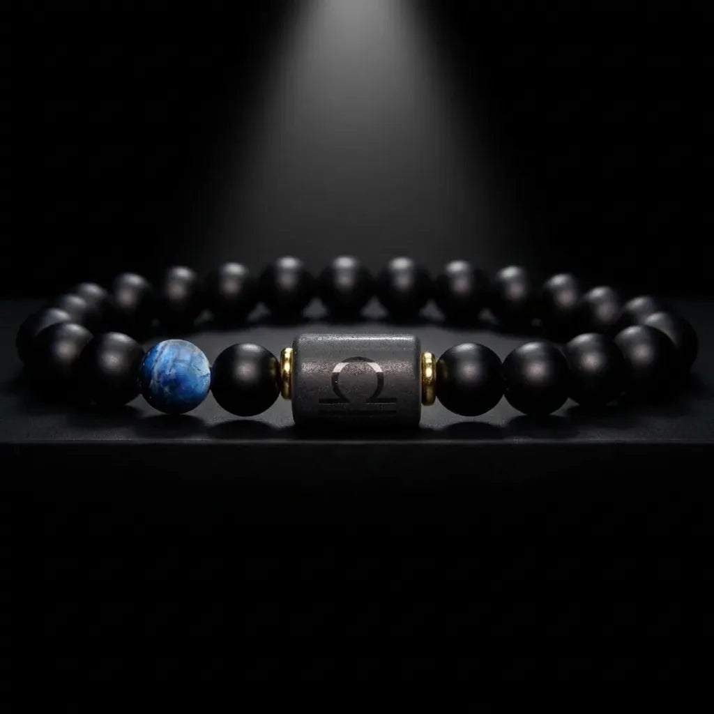Libra zodiac bracelet with matte black beads, blue accent stone, and engraved center bead under spotlight.