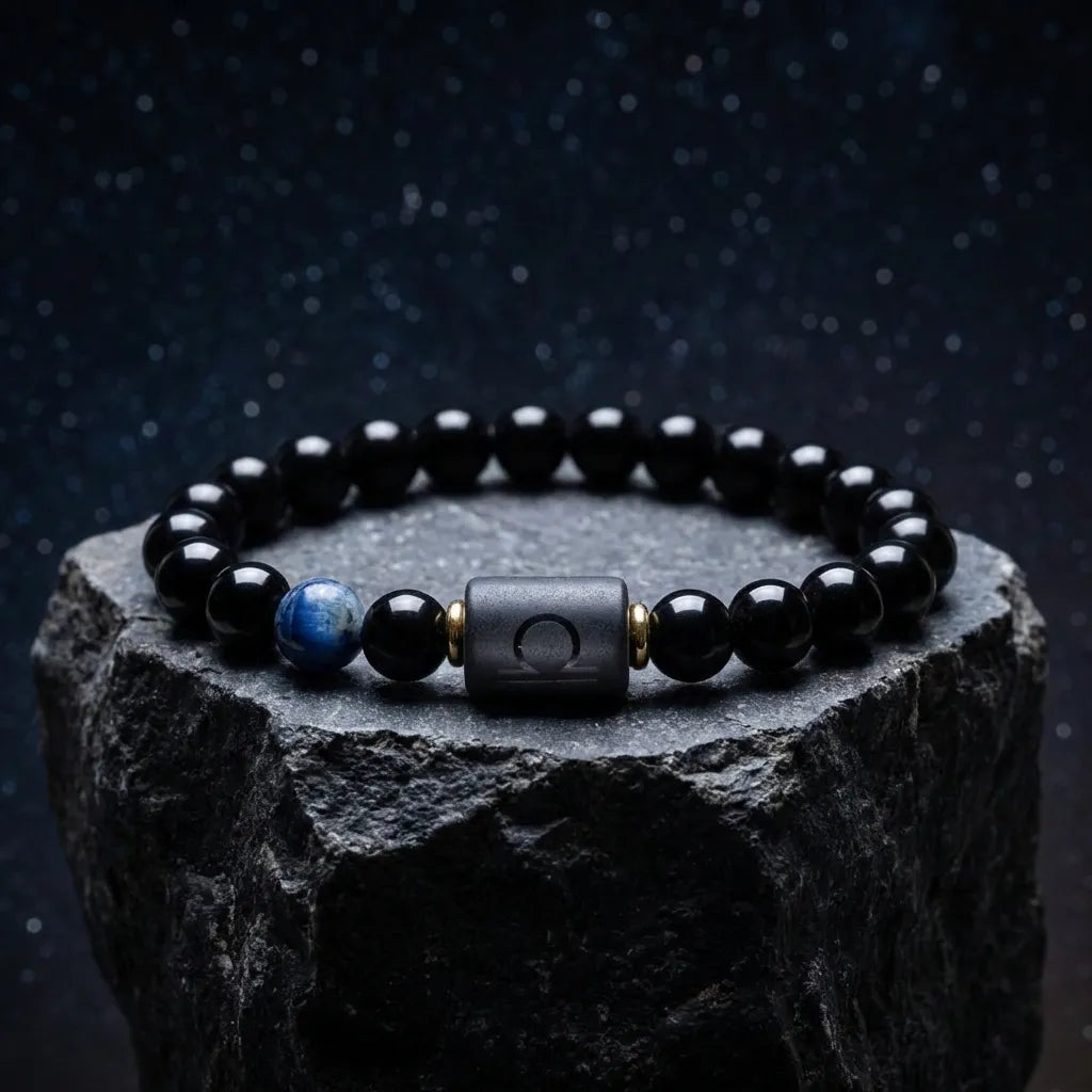 Libra zodiac bracelet with glossy black beads, blue accent stone, and engraved center bead on a stone pedestal.