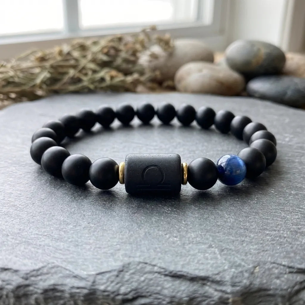Libra zodiac bracelet with matte black beads, blue accent stone, and engraved center bead on gray stone.