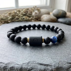 Libra zodiac bracelet with matte black beads, blue accent stone, and engraved center bead on gray stone.
