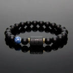 Libra zodiac bracelet with glossy black beads, blue accent stone, and engraved center bead on reflective surface.