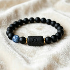 Libra zodiac bracelet with black lava stone center bead, blue accent stone, and matte beads on soft fabric.