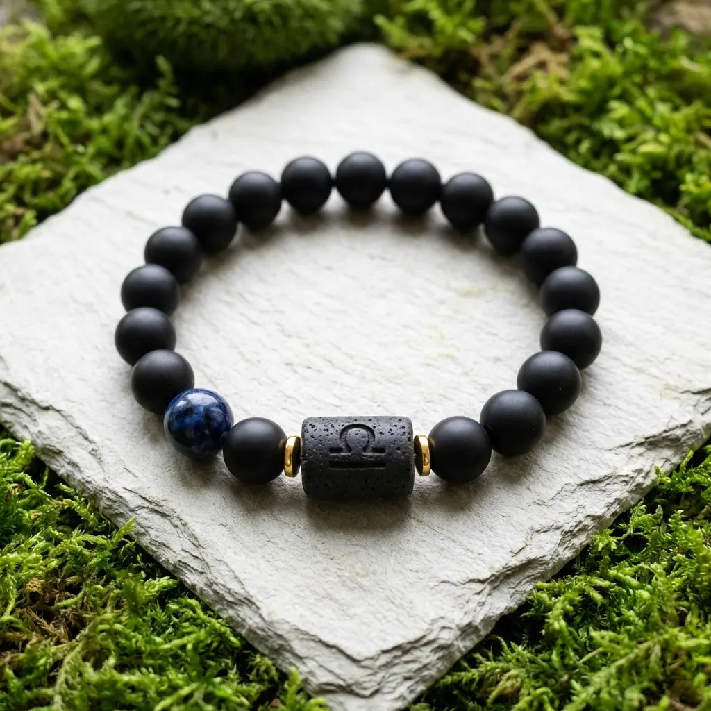Libra zodiac bracelet with matte black beads, blue accent stone, and engraved center bead on stone with moss.