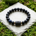 Libra zodiac bracelet with matte black beads, blue accent stone, and engraved center bead on stone with moss.