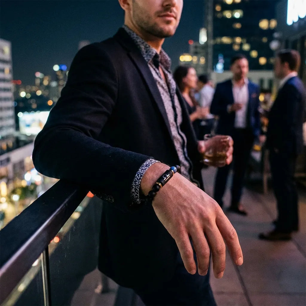 Libra zodiac bracelet worn by a man on a rooftop at night, featuring black beads and blue accent stone.
