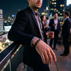 Libra zodiac bracelet worn by a man on a rooftop at night, featuring black beads and blue accent stone.