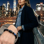 Libra zodiac bracelet worn by a woman on a city bridge at night, featuring black beads and blue accent stone.