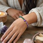 Lotus bracelet worn beside crystals and candles creating soothing gemstone jewelry wellness inspiration