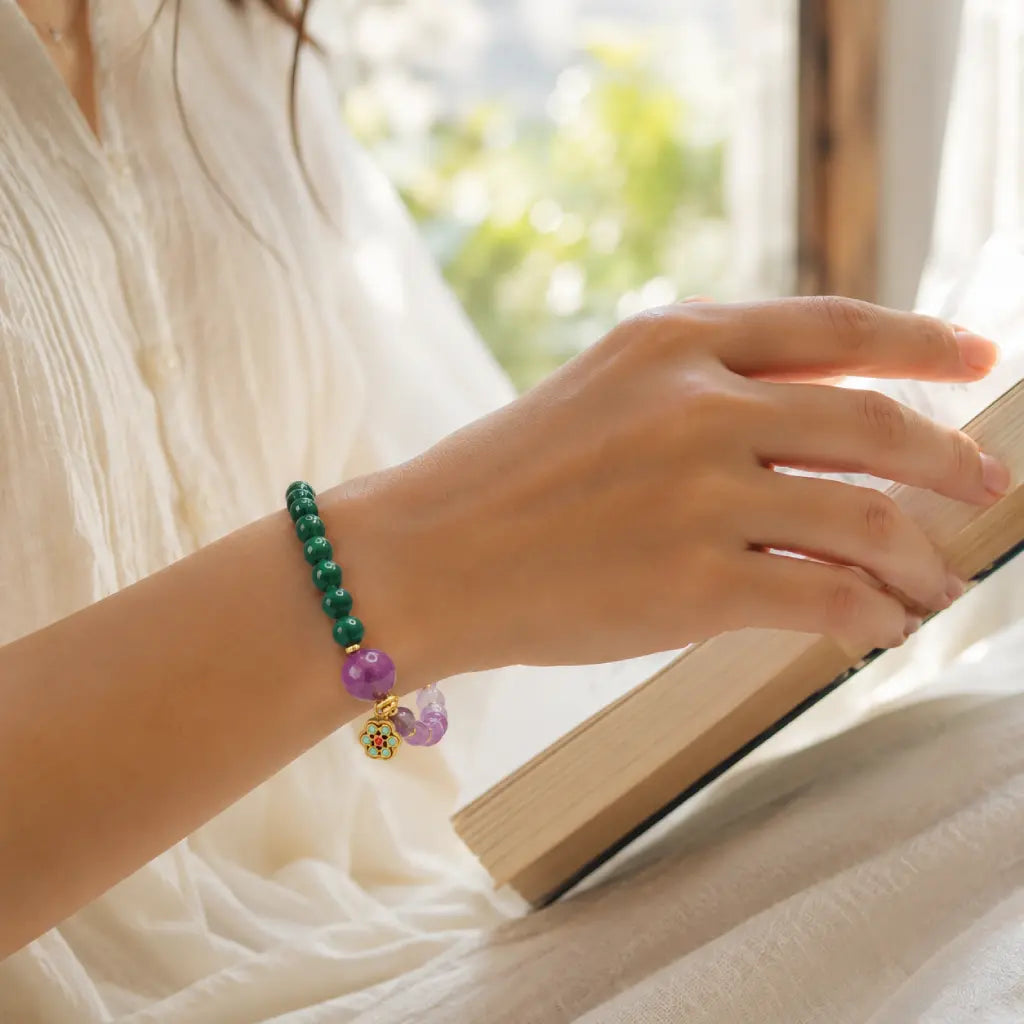 Lotus bracelet featuring gemstone beads worn while reading for peaceful wellness and spiritual elegance