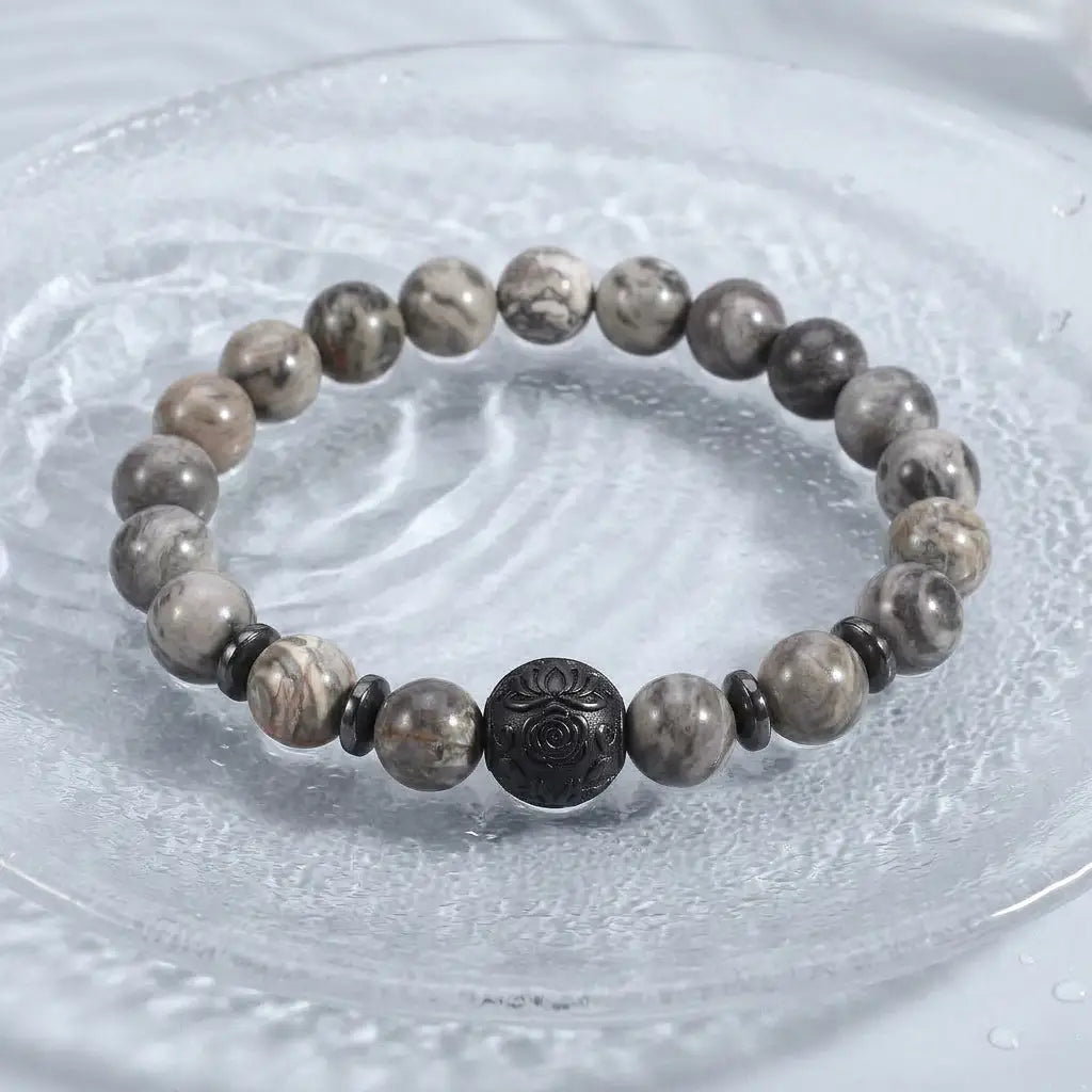 map jasper bracelet on frosted glass plate with gray beads and carved black charm for serene crystal style gift