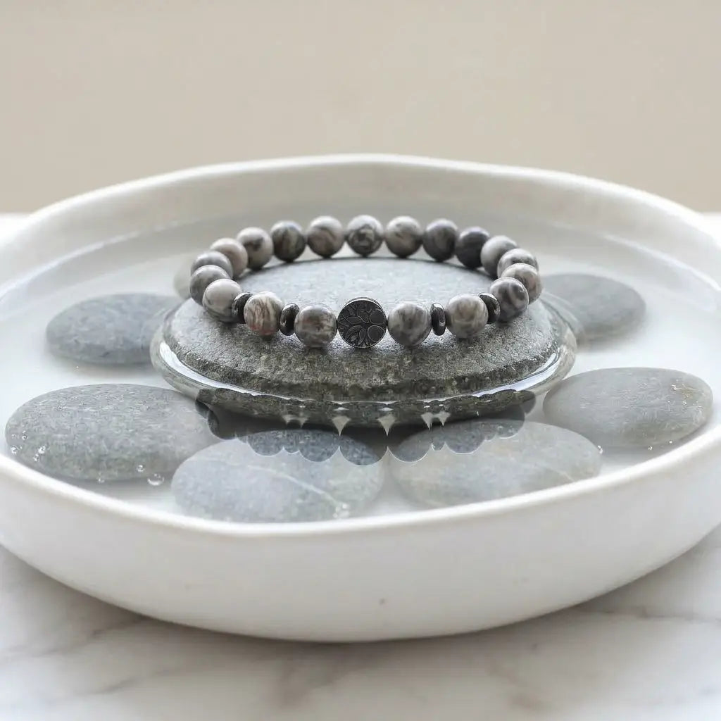map jasper bracelet on stone in water bowl with smooth pebbles, calming gemstone jewelry for balance and mindful living