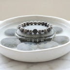 map jasper bracelet on stone in water bowl with smooth pebbles, calming gemstone jewelry for balance and mindful living