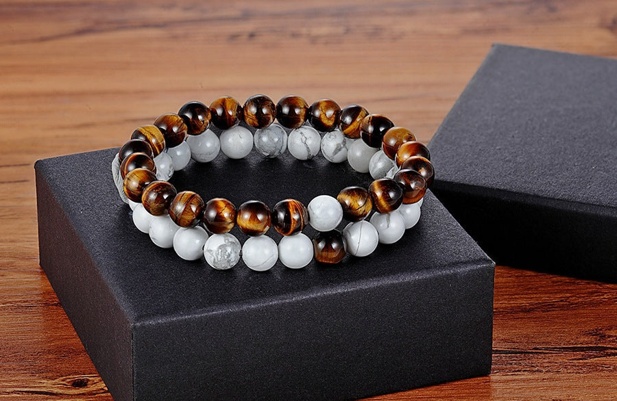 Matching bead bracelets for couples arranged as two coordinated glass-bead strands, pairing amber-brown striped beads with white marbled round beads on a black display box in view.