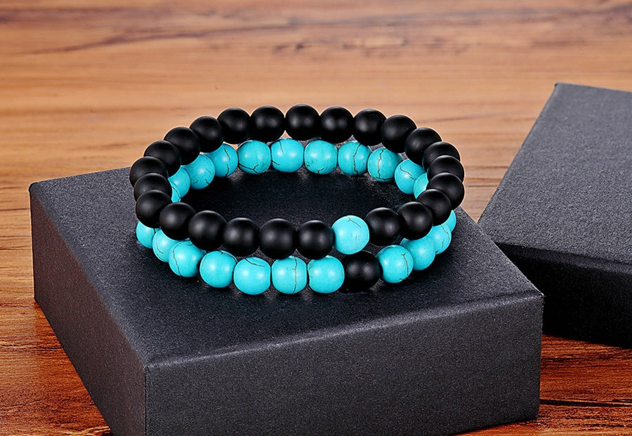 Matching bead bracelets for couples shown as two coordinated glass-bead strands, pairing matte black round beads with turquoise-color marbled beads on a black display box together.