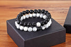 Matching bead bracelets for couples displayed as two coordinated glass-bead strands, with black speckled round beads and white marbled round beads resting on a black gift box here.