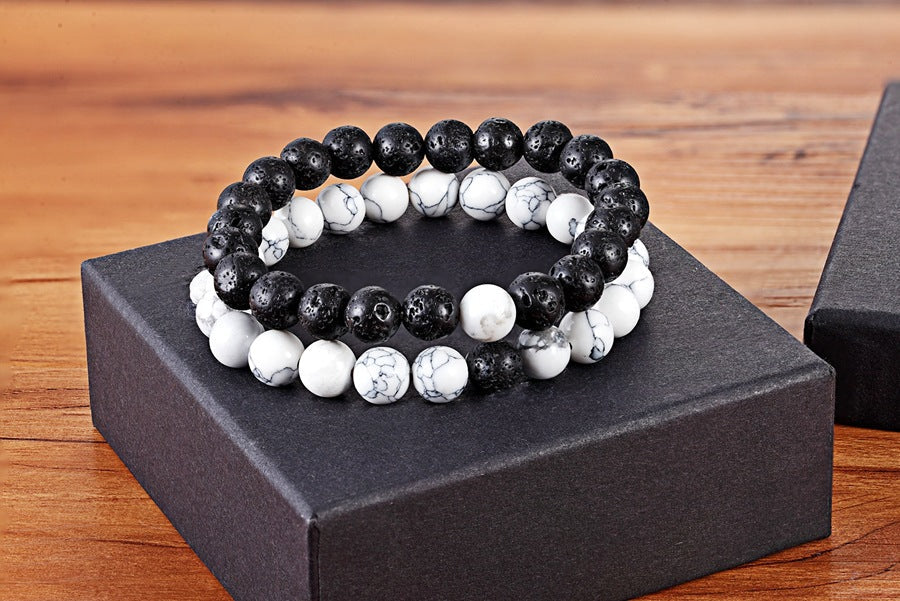 Matching bead bracelets for couples displayed as two coordinated glass-bead strands, with black speckled round beads and white marbled round beads resting on a black gift box here.