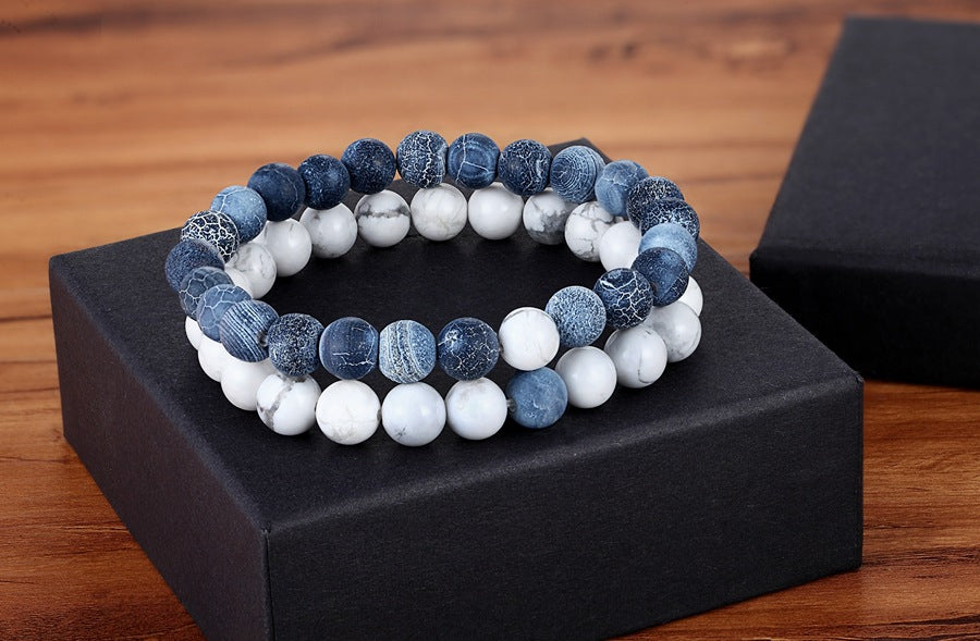 Matching bead bracelets for couples displayed as two coordinated glass-bead strands, pairing textured denim-blue round beads with white marbled beads on a black gift box as a pair.