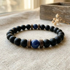 Matte black onyx lapis lazuli bead bracelet on natural linen with dried flowers and soft window light, artisan boho gemstone wrist jewelry