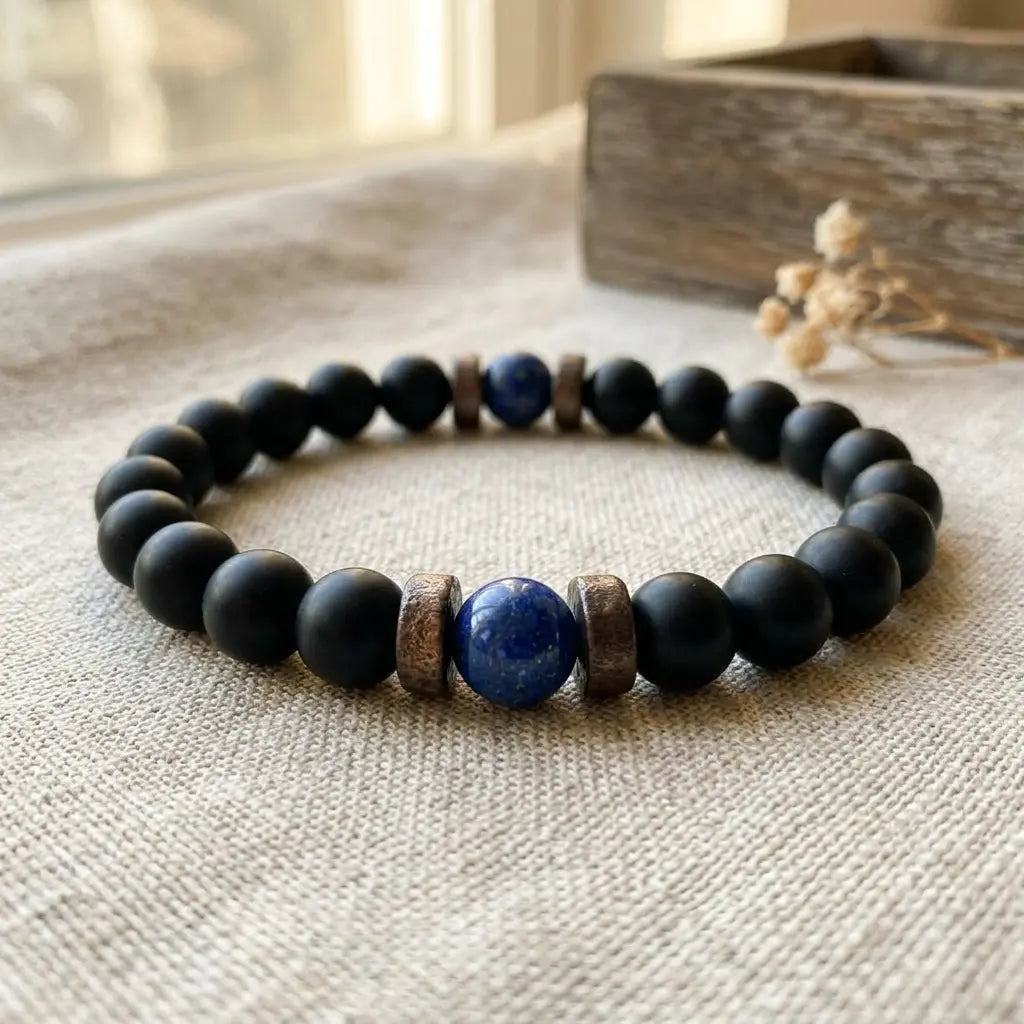 Matte black onyx lapis lazuli bead bracelet on natural linen with dried flowers and soft window light, artisan boho gemstone wrist jewelry