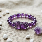 Natural amethyst bracelet with Pixiu charm on natural stone display featuring crystal jewelry energy