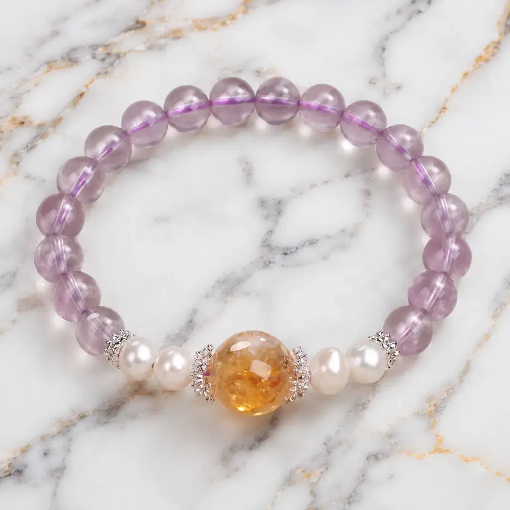 Natural ametrine citrine bracelet with polished gemstone beads and pearl accents on marble display.