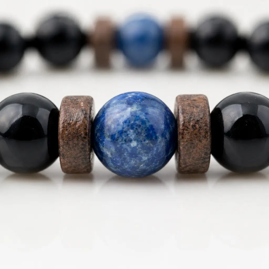 Obsidian lapis lazuli bracelet macro showing the natural blue gemstone centerpiece with polished black beads and handcrafted details.