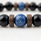 Obsidian lapis lazuli bracelet macro showing the natural blue gemstone centerpiece with polished black beads and handcrafted details.