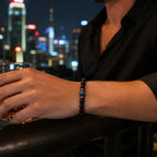 Obsidian lapis lazuli bracelet paired with evening attire against a city skyline, highlighting polished gemstone craftsmanship.