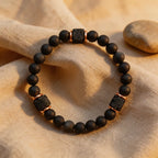 Black beaded bracelet with lava rock accents on a beige fabric background