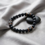 Black onyx lava beaded bracelet with copper accents on a gray fabric background