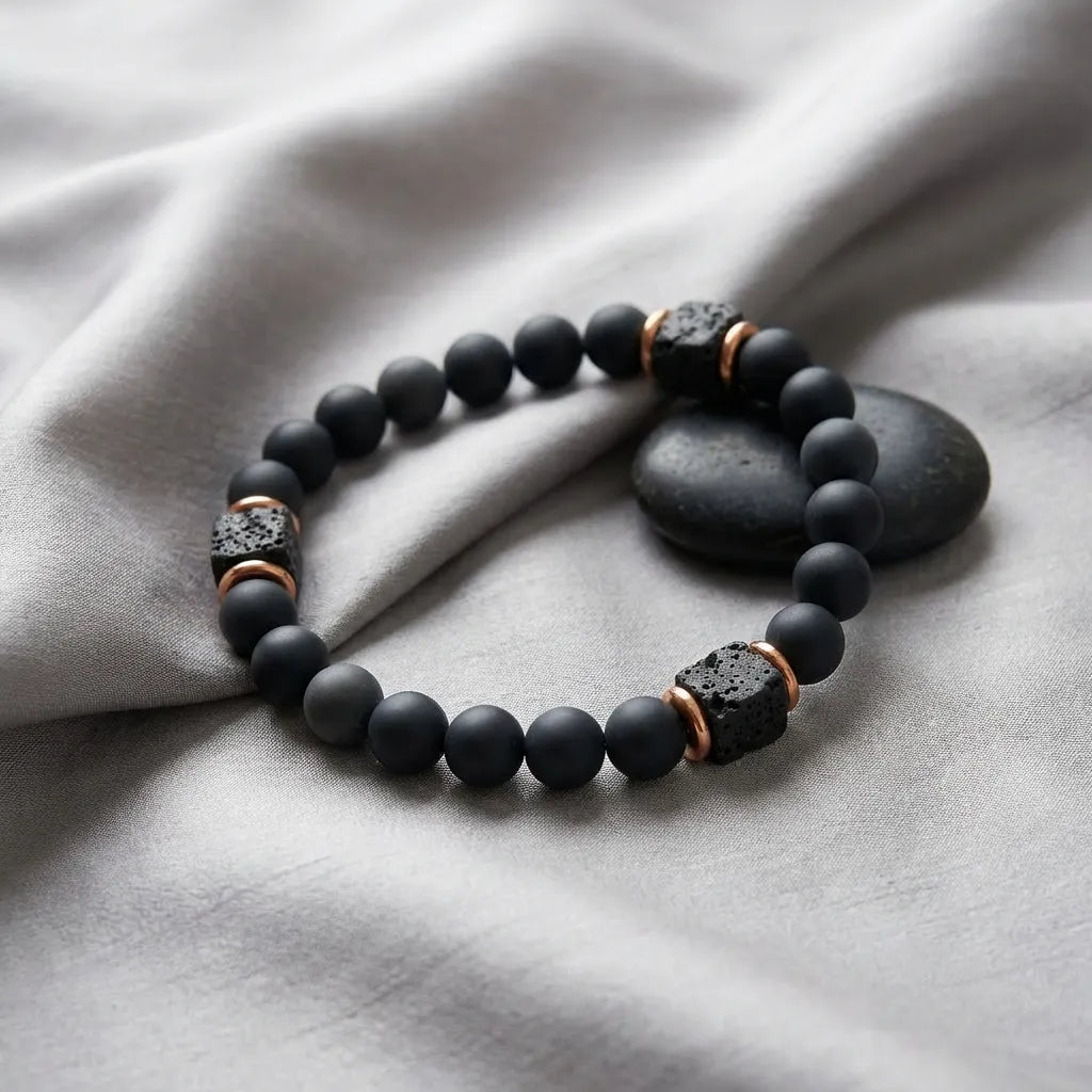 Black onyx lava beaded bracelet with copper accents on a gray fabric background