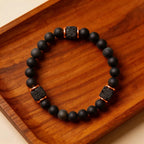 Black beaded bracelet with lava rock accents on a wooden surface