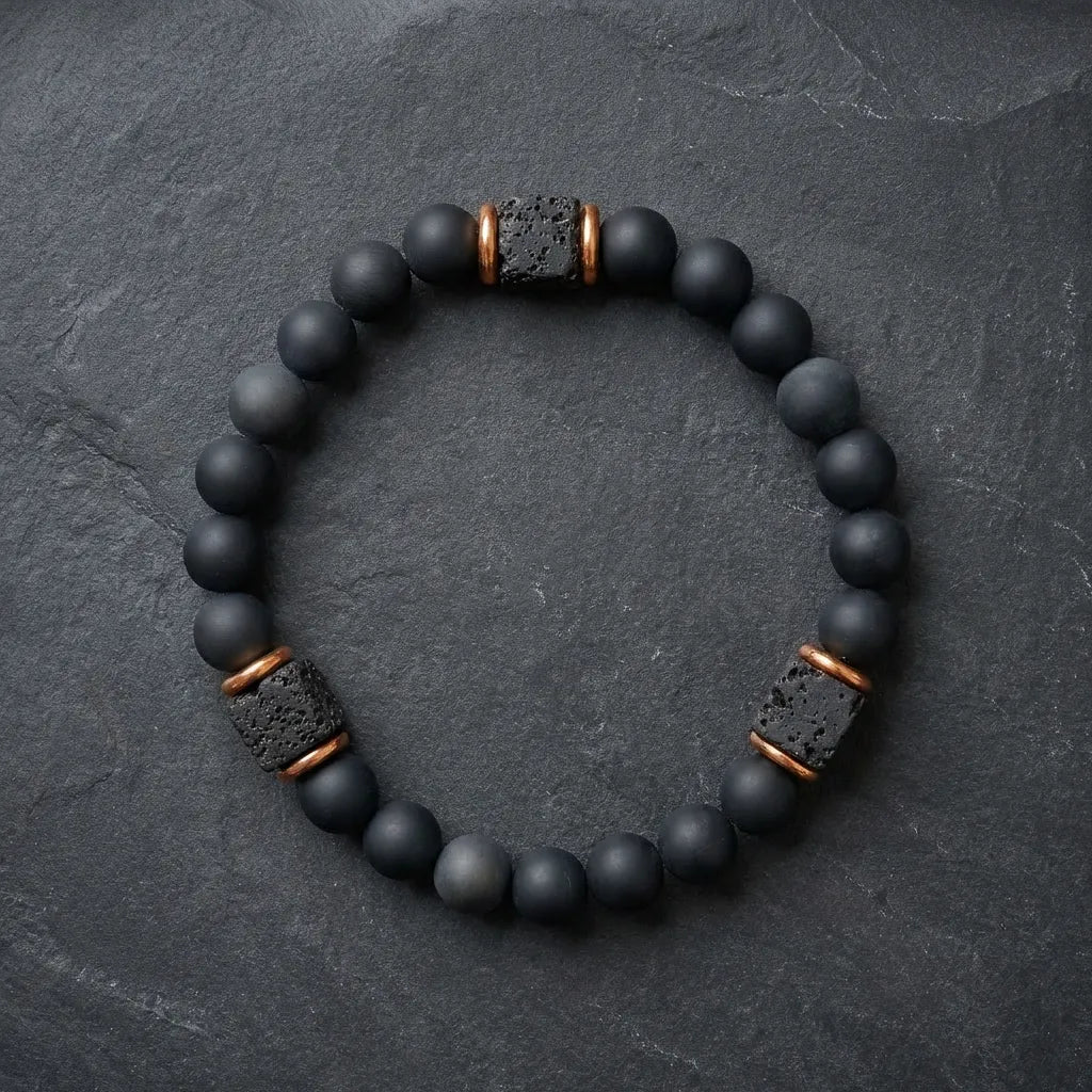 Black onyx lava bracelet with metallic accents on a dark stone background