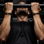 Onyx stone bracelet on wrist lifting dumbbell, symbolizing power, resilience, and premium fitness jewelry for intense training