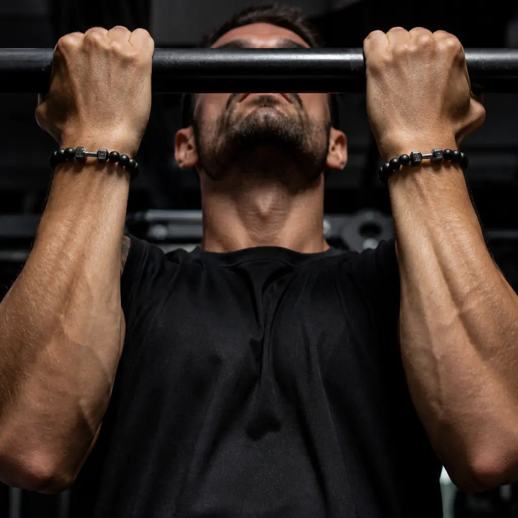 Onyx stone bracelet on wrist lifting dumbbell, symbolizing power, resilience, and premium fitness jewelry for intense training