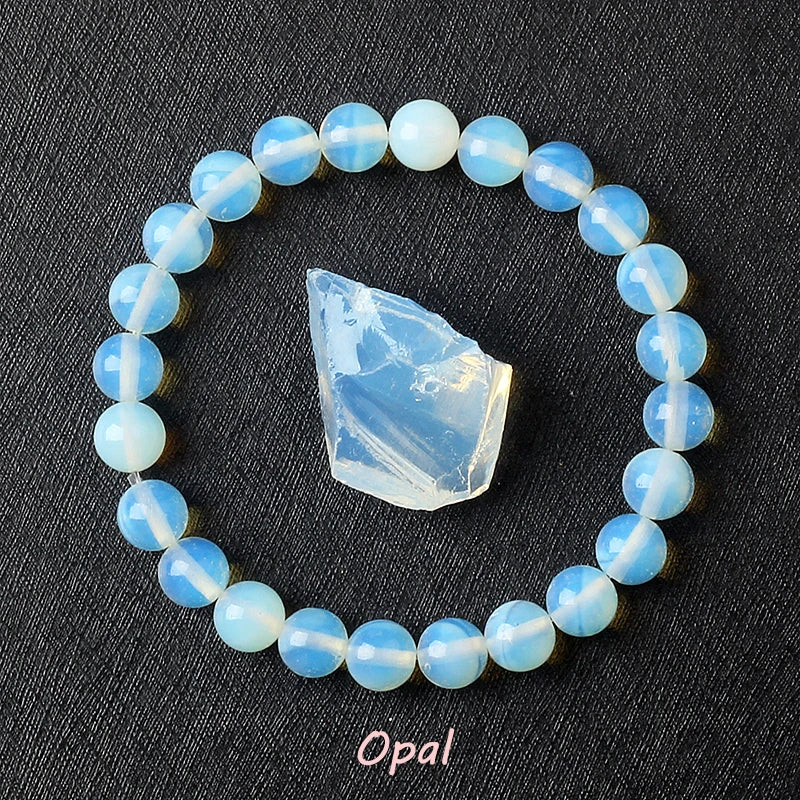 Opal bracelet with soft blue-white opalescent beads surrounding a raw pale opalite specimen on dark background