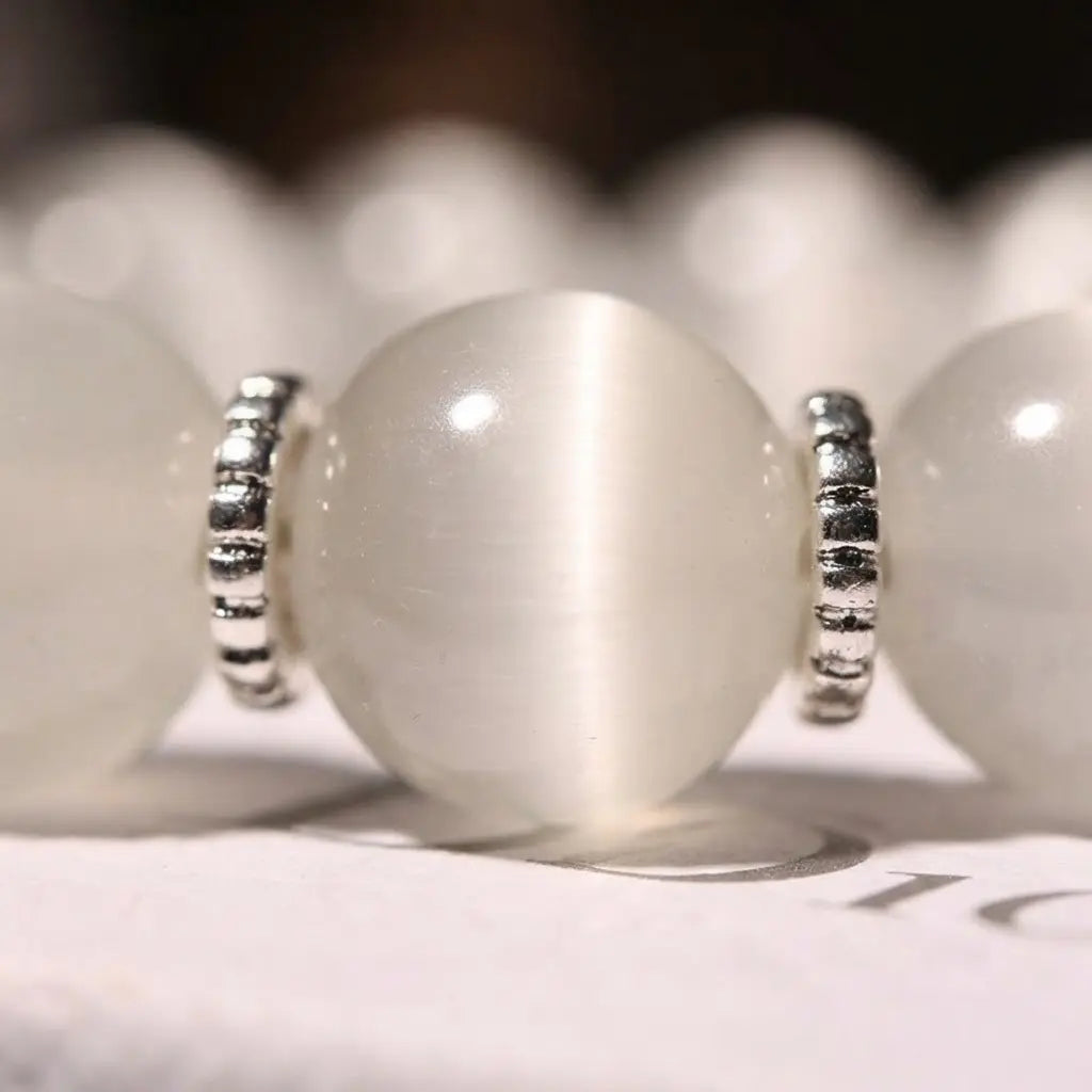 Close-up of the Moonlit Inspiration Opal Bracelet showing a luminous white Opal bead beside silver-tone spacer details, with a polished finish and soft moonlit glow in crisp focus.