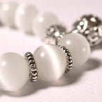 Macro view of the Moonlit Inspiration Opal Bracelet showing luminous white natural Opal beadwork and ornate silver-tone spacer details, with a smooth polished finish and soft glow.
