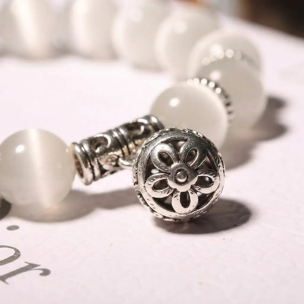 Close-up of the Moonlit Inspiration Opal Bracelet highlighting its ornate silver-tone floral charm, luminous white Opal beads, and decorative spacer details in crisp product focus.