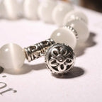 Close-up of the Moonlit Inspiration Opal Bracelet highlighting its ornate silver-tone floral charm, luminous white Opal beads, and decorative spacer details in crisp product focus.