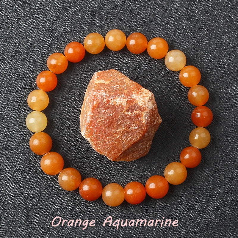 Orange Aquamarine bracelet with warm tangerine beads beside a raw stone, symbolically linked to Sacral Chakra creativity