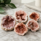Pink amethyst geode collection with multiple natural crystal specimens displaying sparkling druzy interiors for luxury home décor.