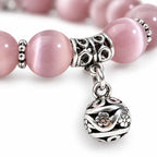 Pink Catseye bracelet featuring luminous pink cat eye beads, silver spacers and an ornate charm for polished elegance.